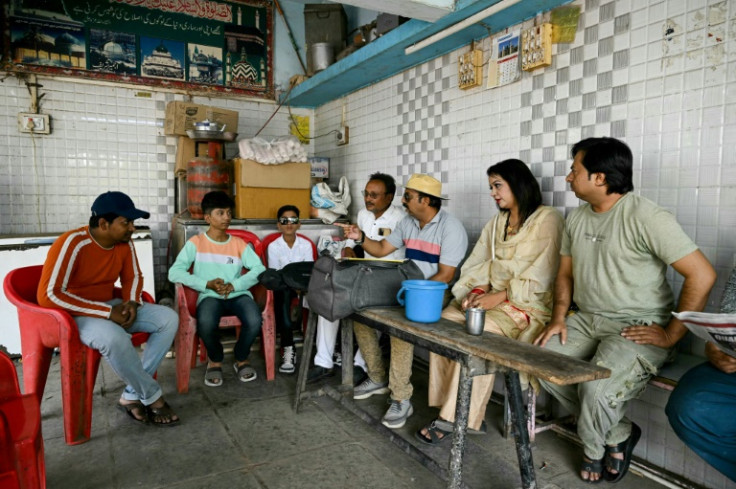 Actor Roma Momin (2nd R) meets with the director and crew of an upcoming movie at a tea stall in Malegaon