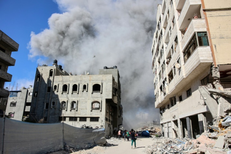 Palestinians in Gaza City watch as smoke rises from a building hit by a strike after an Israeli army warning for its occupants to evacuate