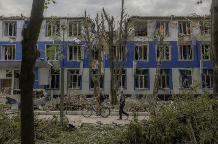 People walk past a heavily damaged university building following an attack in Pokrovsk, in the eastern Donetsk region, on August 4, 2024, amid the Russian invasion of Ukraine. The industrial Donbas region has long been a key prize for the Kremlin. A decad