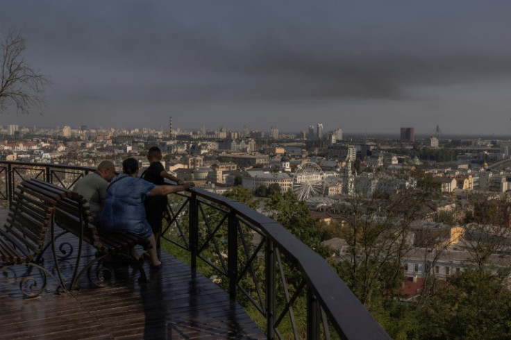A man, a woman and a child look on as smoke rises over buildings in Kyiv following the Russian air attack across Ukraine