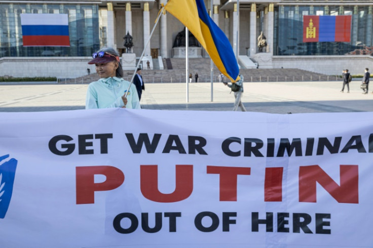 A woman holding a Ukranian national flags and a banner takes part in a protest ahead of a visit by Russian President Vladimir Putin in Ulaanbaatar, Mongolia's capital city on September 2, 2024.