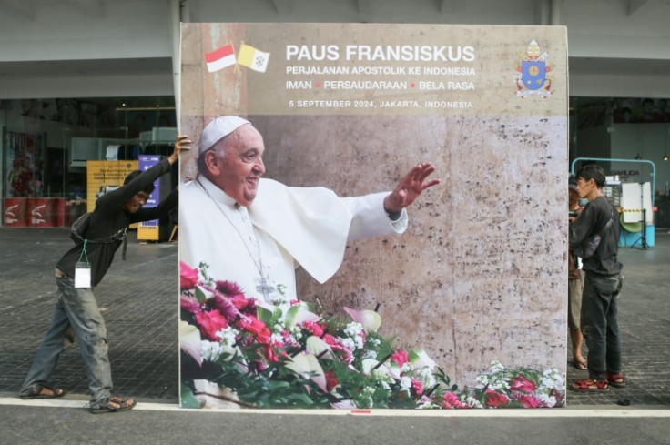 Workers install a billboard for the upcoming mass that will be led by Pope Francis in Jakarta