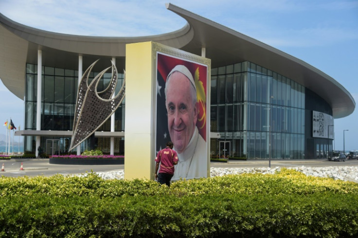 A man walks next to a giant portrait of Pope Francis at the APEC Haus in Port Moresby