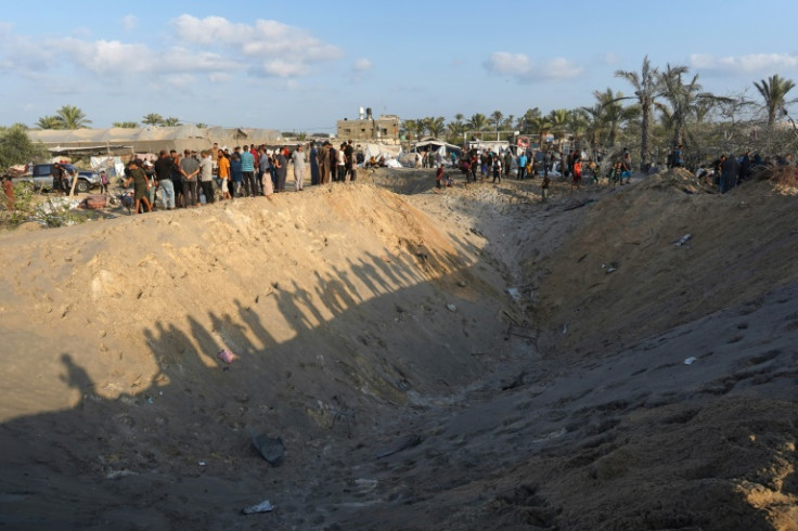 Palestinians stand on the edge of a crater in the Al-Mawasi displacement camp in the Gaza Strip