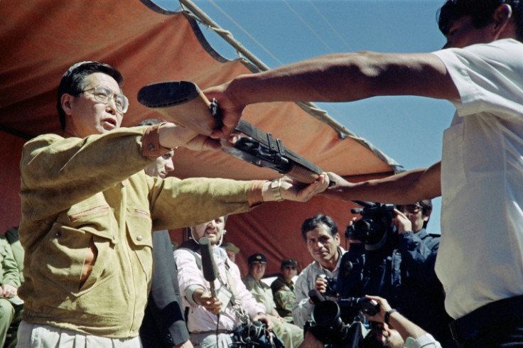 Peru's then-president Alberto Fujimori hands a weapon to a man in 1991 for use in the battle against the Shining Path leftist rebels. He died on Wednesday at the age of 86 in Lima