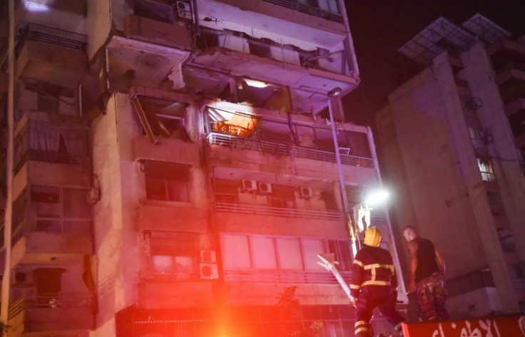 Firefighters check the balcony of an apartment building hit by an Israeli air strike in Beirut's Kola district