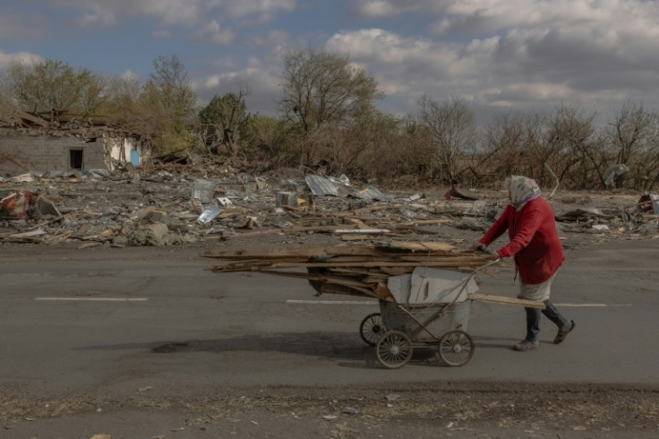 A Ukrainian woman collects wood amid damage from shelling in the village of Yasenove, south of Pokrovsk