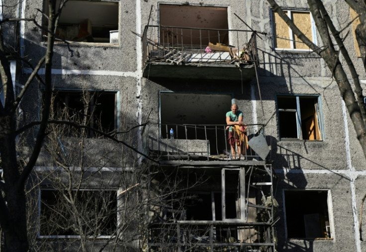A resident stands on the balcony of an apartment building damaged in an overnight Russian strike in the Donetsk region