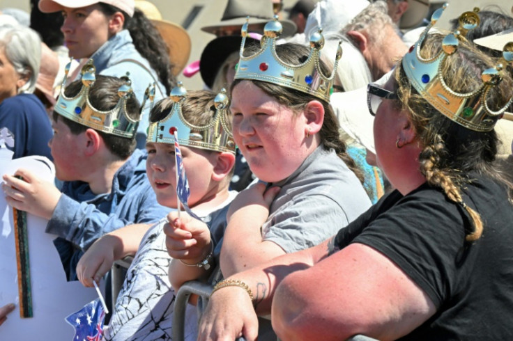 People wearing crowns wait for Britain's King Charles III and Queen Camilla outside Parliament House in Canberra