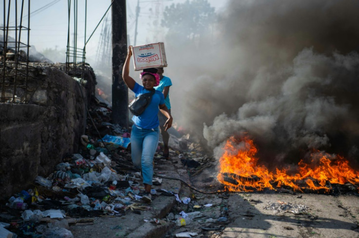 People walk past burning tires, during a demonstration against insecurity in Port-au-Prince, Haiti, August 19, 2024