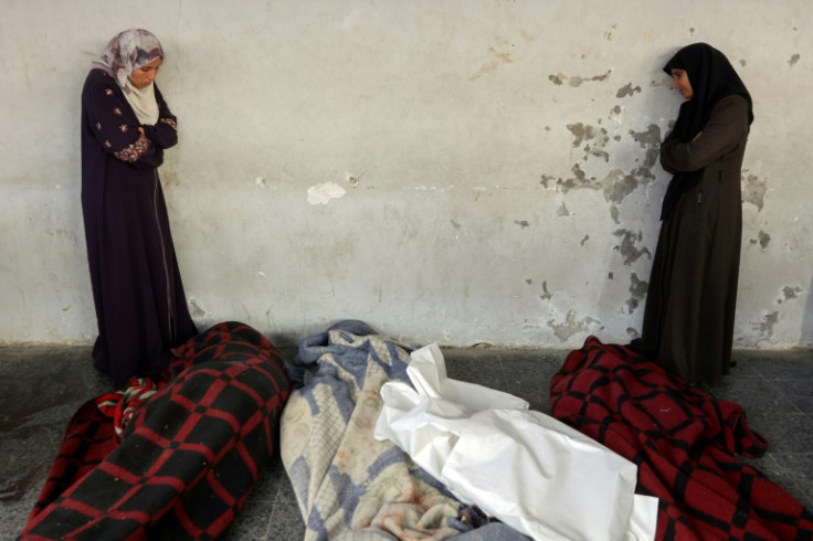 Women mourn next to bodies wrapped in blankets at a hospital morgue in Gaza City on Friday