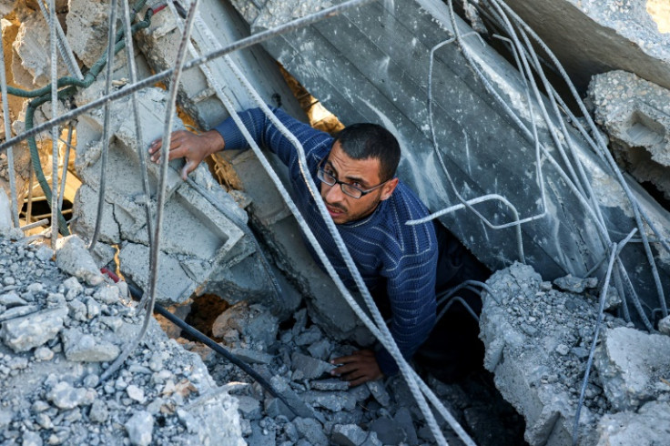 A man climbs out of rubble in a search for survivors at the site of an Israeli strike in southern Gaza's Khan Yunis