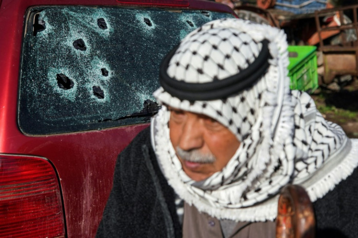 A Palestinian man near a bullet-riddled car in Burqin village, where Israeli troops killed two militants wanted for murder