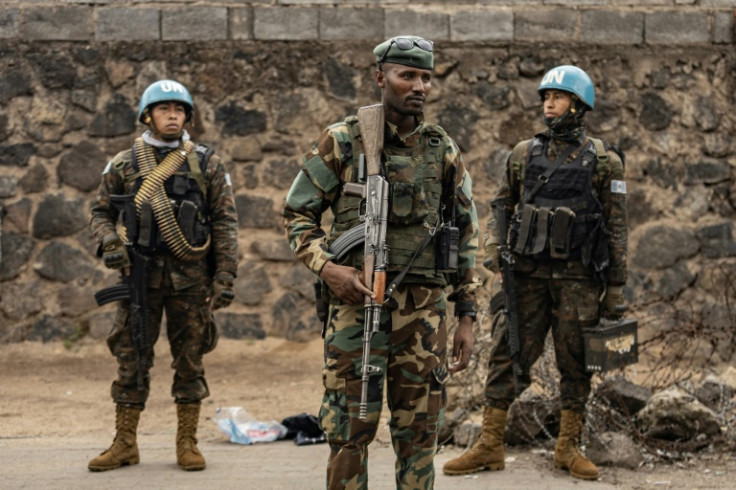 An M23 fighter stands in front of UN peacekeepers in Goma