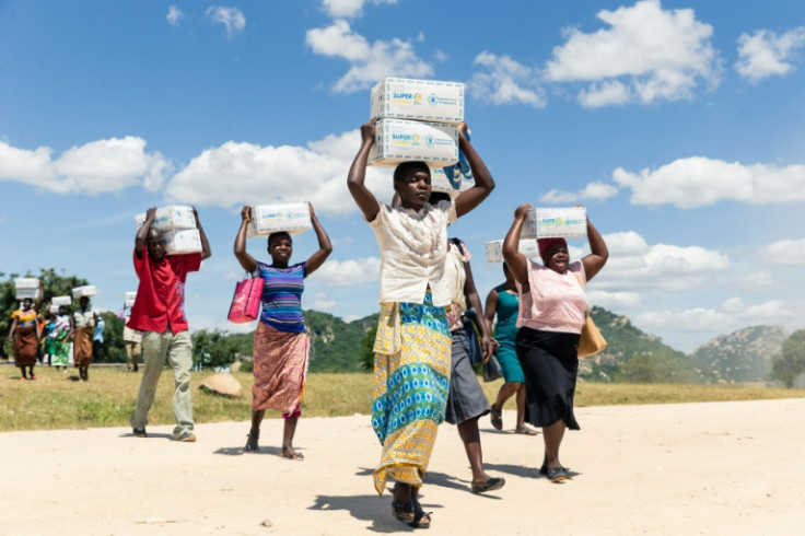 Mothers carry boxes of porridge backed by US aid in the Mutokoarea of Zimbabwe in 2019 as drought worsened hunger