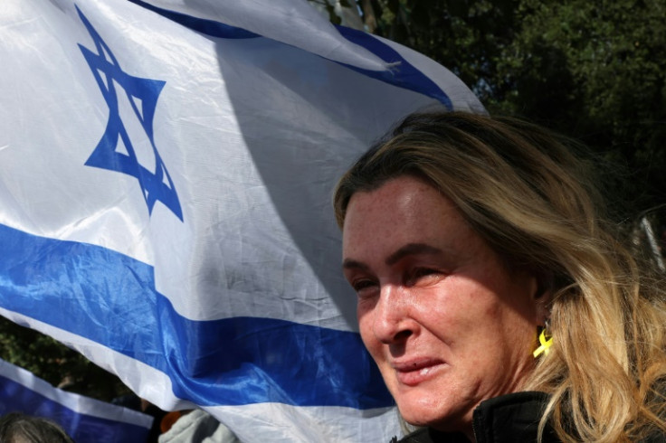 An onlooker holding an Israeli flag cries as a convoy transporting the bodies of dead hostages arrives in Tel Aviv on Thursday