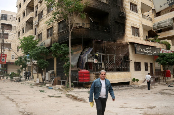 A man walks past a partially burnt building following sectarian clashes in Ashrafiyat Sahnaya near Damascus