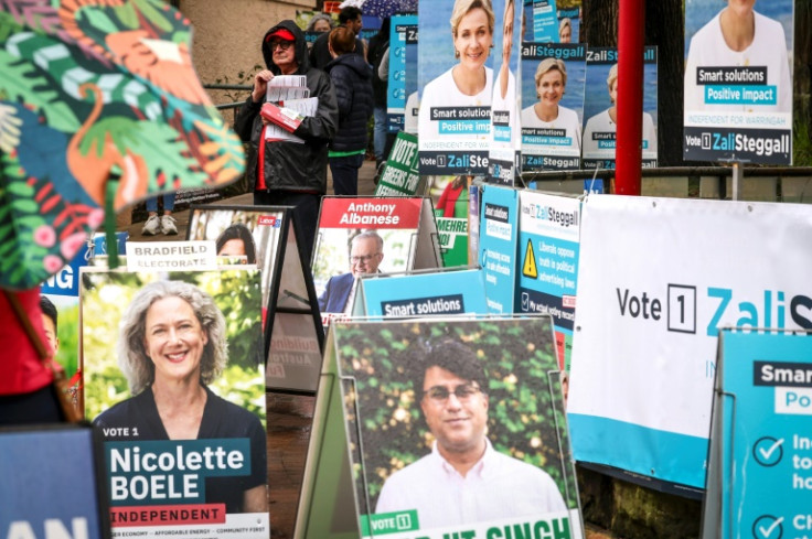 Volunteers hand out voting cards next to election candidate posters in Sydney