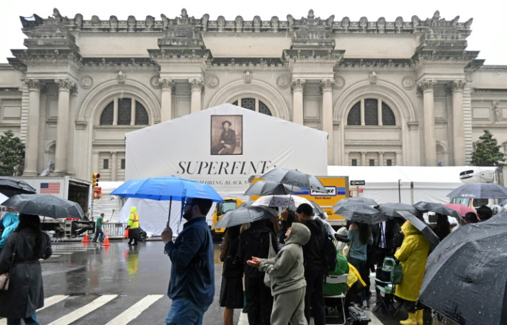 People walk through the rain outside the Met before the 2025 Met Gala at the Metropolitan Museum of Art in New York