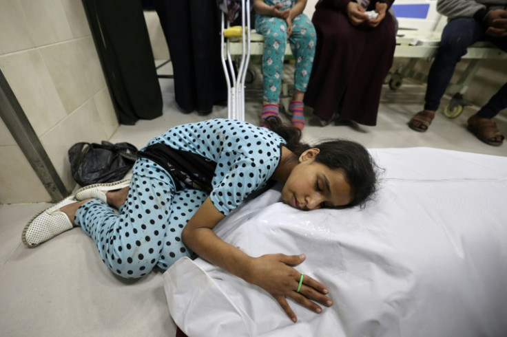 A Palestinian girl mourns over the shrouded body of her mother, killed in a strike