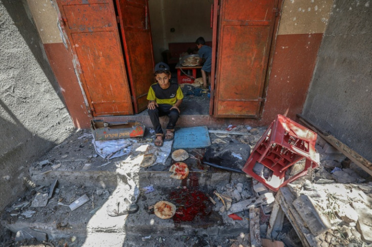Palestinian boys salvage bread from a makeshift bakery hit in Israeli strikes at the Nuseirat refugee camp in the central Gaza Strip on May 8, 2025