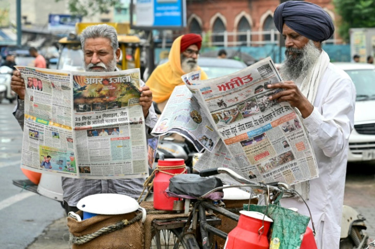 Men read local newspapers with frontpage articles on India-Pakistan conflict in Amritsar on May 8, 2025 a day after India launched strikes on Pakistan