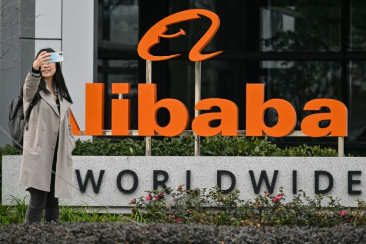 A woman poses for a selfie next to a sign for e-commerce giant Alibaba in the Xuhui district of Shanghai in February
