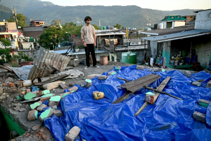 A man stands on the roof of his damaged home