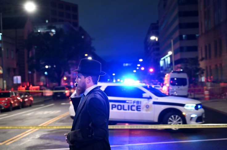 A man, standing behind police tape, talks on his cell phone outside the Capital Jewish Museum following a shooting that left two people dead, in Washington