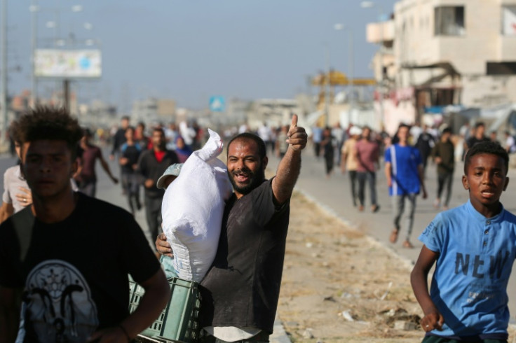 A man carries a bag of food aid while others rush to get a share after people stormed a World Food Programme warehouse in Deir el-Balah in Gaza on May 28, 2025
