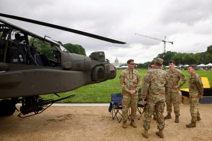 Soldiers gather next to an US Army AH-64 Apache helicopter on display on the National Mall during the Army 250th anniversary celebration