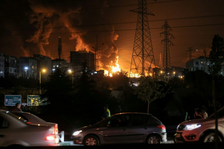Vehicles jam a highway as a fire blazes nearby in the oil depots of Shahran, northwest of Tehran