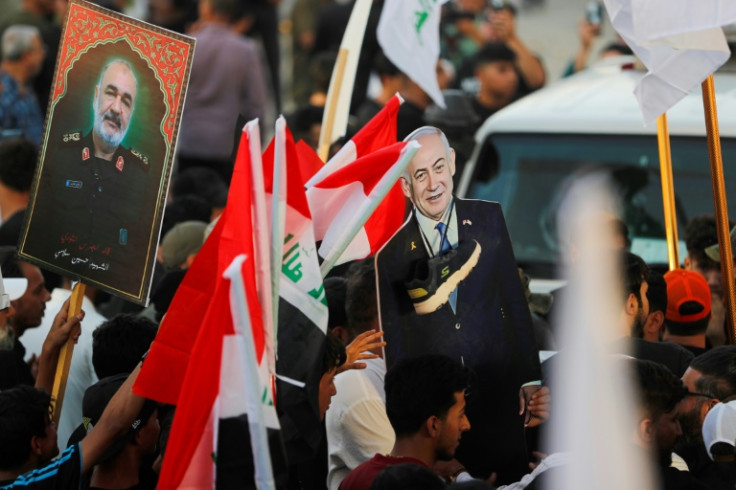 An Iraqi holds a picture of Major General Hossein Salami, head of the Iranian Revolutionary Guard, who was killed in an Israeli airstrike in Tehran, with another holding a cutout of Israeli Prime Minister Benjamin Netanyahu with a shoe around the neck dur