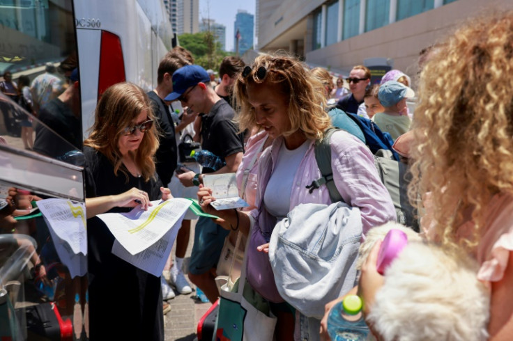 People register before the departure of a bus slated to evacuate foreign passport holders, mainly European and Polish, out of Israel, at a meeting point in Tel Aviv