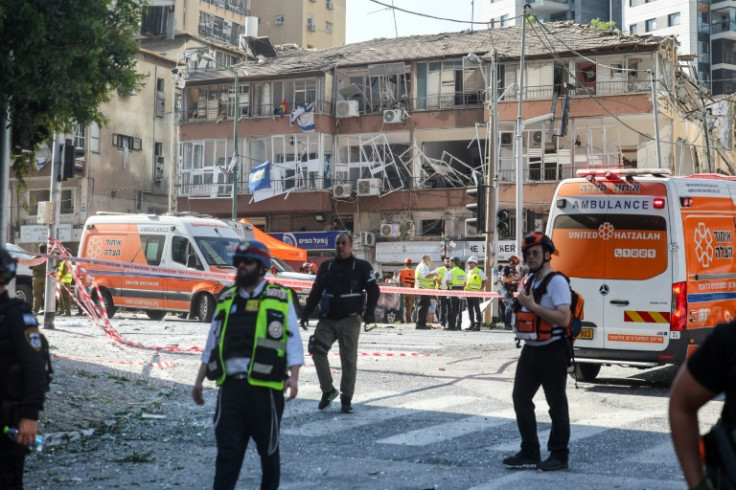 Israeli emergency services stand in front of a building damaged in an Iranian missile attack