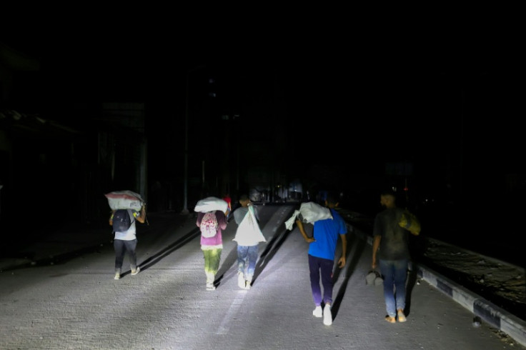 Palestinians carry parcels collected from a food aid distribution point set up by the Gaza Humanitarian Foundation