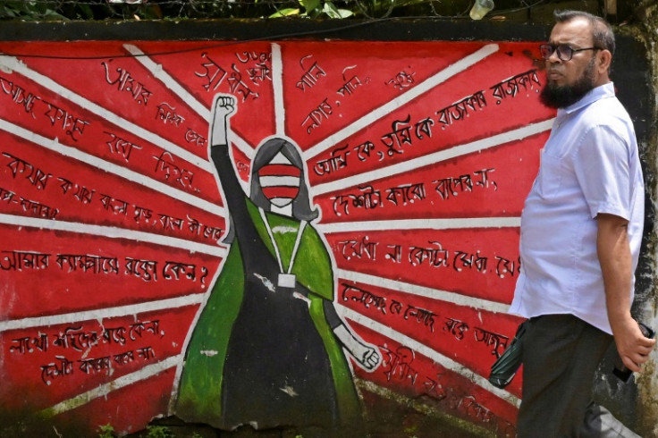 In this picture taken on June 18, 2025, a Bangladeshi man walks past anti-government wall murals along a road in Dhaka. Bangladesh on July 1, 2025 marks one year since students launched protests that culminated weeks later in the overthrow of the governme