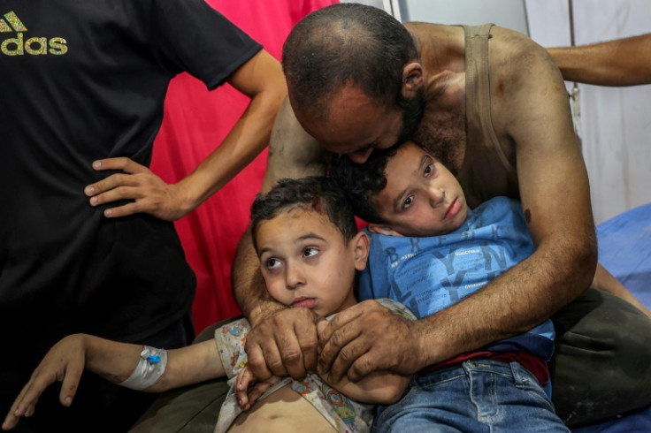 A man embraces two injured boys as they sit on a bed at al-Awda Hospital in Gaza's Nuseirat refugee camp on Sunday