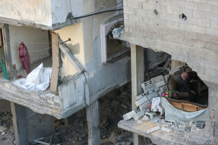 A Palestinian woman clears debris from her home as he neighbour inspects the damage after an Israeli strike on the Al-Shati refugee camp, west of Gaza City, on July 9, 2025