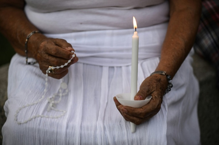 A person in San Antonio, Texas holds a rosary and a candle during a vigil for the victims of catastrophic flooding along the Guadalupe River