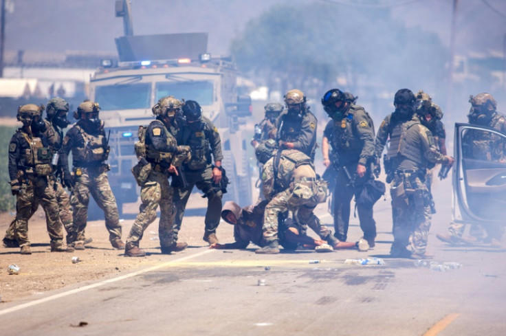US Customs and Border Protection officers make an arrest after pulling a person out of their vehicle outside an immigation raid at Glass House Farms in Camarillo, California