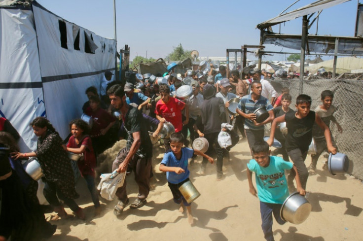 Palestinians rush to queue in line at a charity kitchen in the Mawasi area of Khan Yunis in the southern Gaza Strip on July 22, 2025