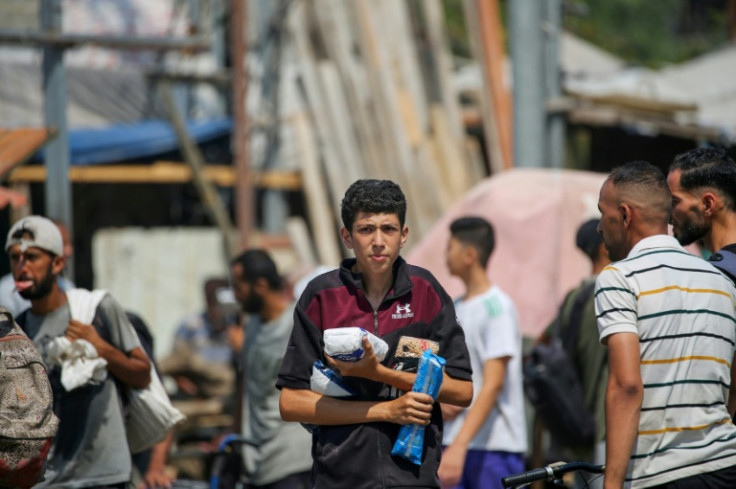 Palestinians return to Gaza's Nuseirat refugee camp with food they have managed to obtain from a distribution point in the Israeli-controlled Netzarim Corridor.
