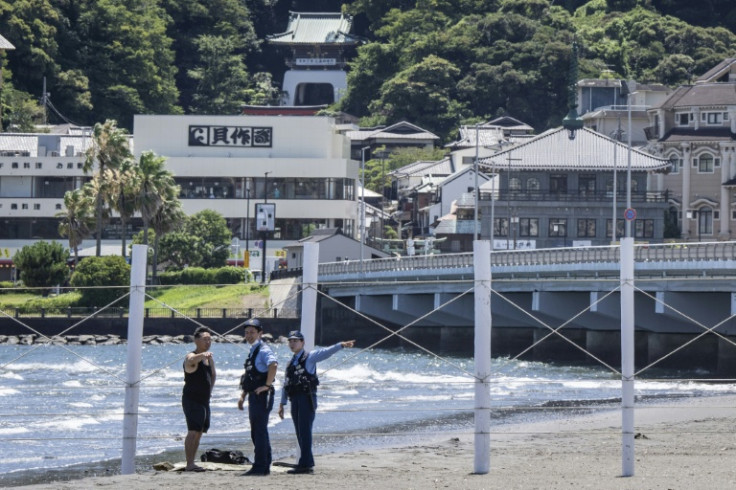 Police ask a man to leave a beach in Fujisawa city, Japan, after the tsunami warning