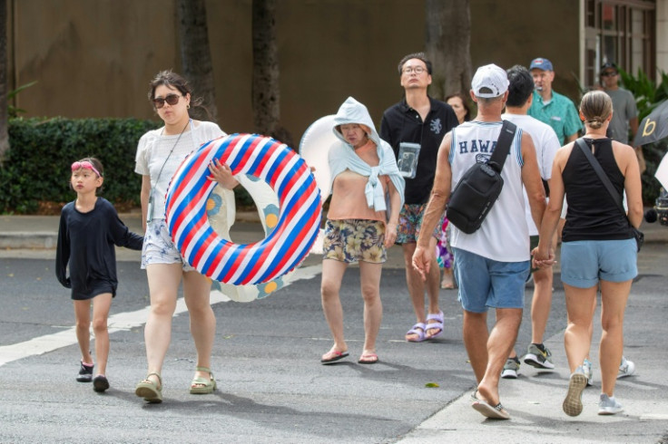 Beachgoers cross the street in Oahu, Hawaii after being told to evacuate following the tsunami warning