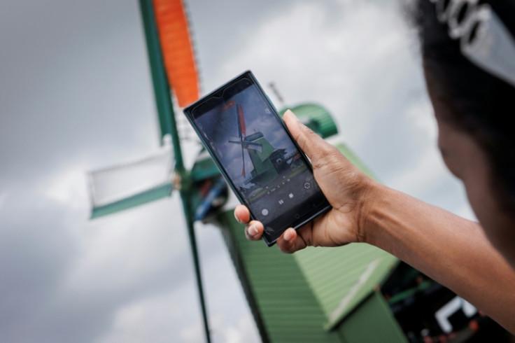 Tourists photograph a windmill at Zaanse Schans, near Amsterdam, on July 31, 2025. The TikTok-famous village may soon charge an entry fee as officials cite rising overtourism.