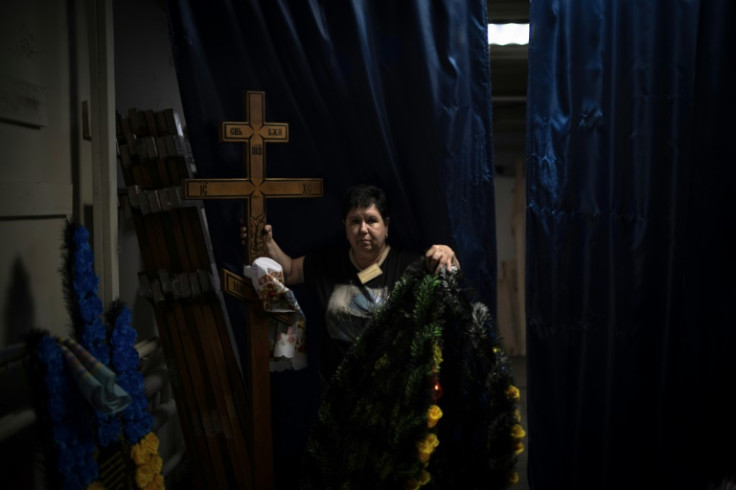 Svitlana Ostapenko prepares a cross and wreaths for the funeral of a soldier