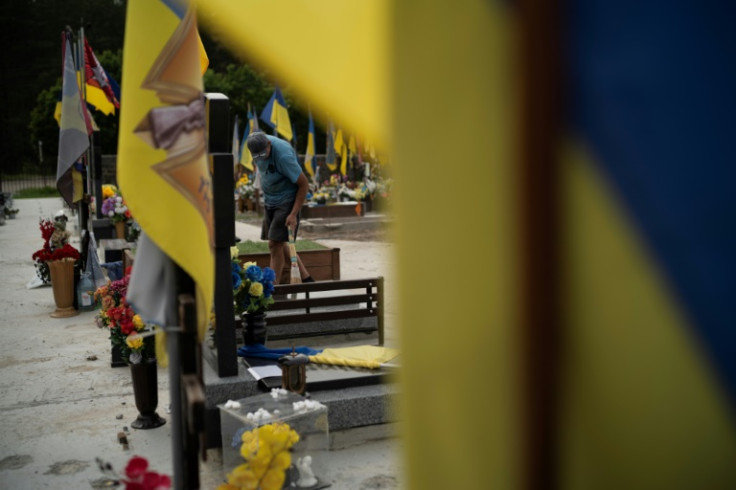 A funeral worker cleans a new grave at a cemetery in Sumy