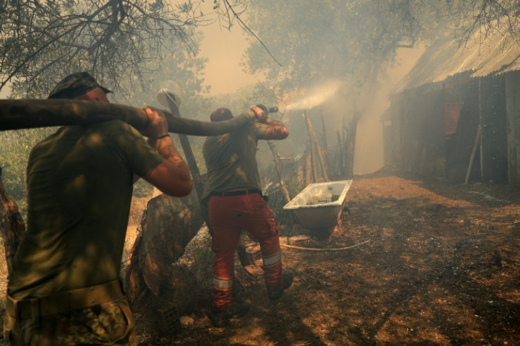 Firefighters spray water on a fire at a house in the town of Delvine, southeast Albania