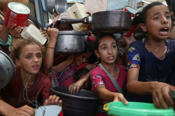 Palestinian children gather to receive cooked meals from a food distribution centre in the Nuseirat refugee camp in central Gaza